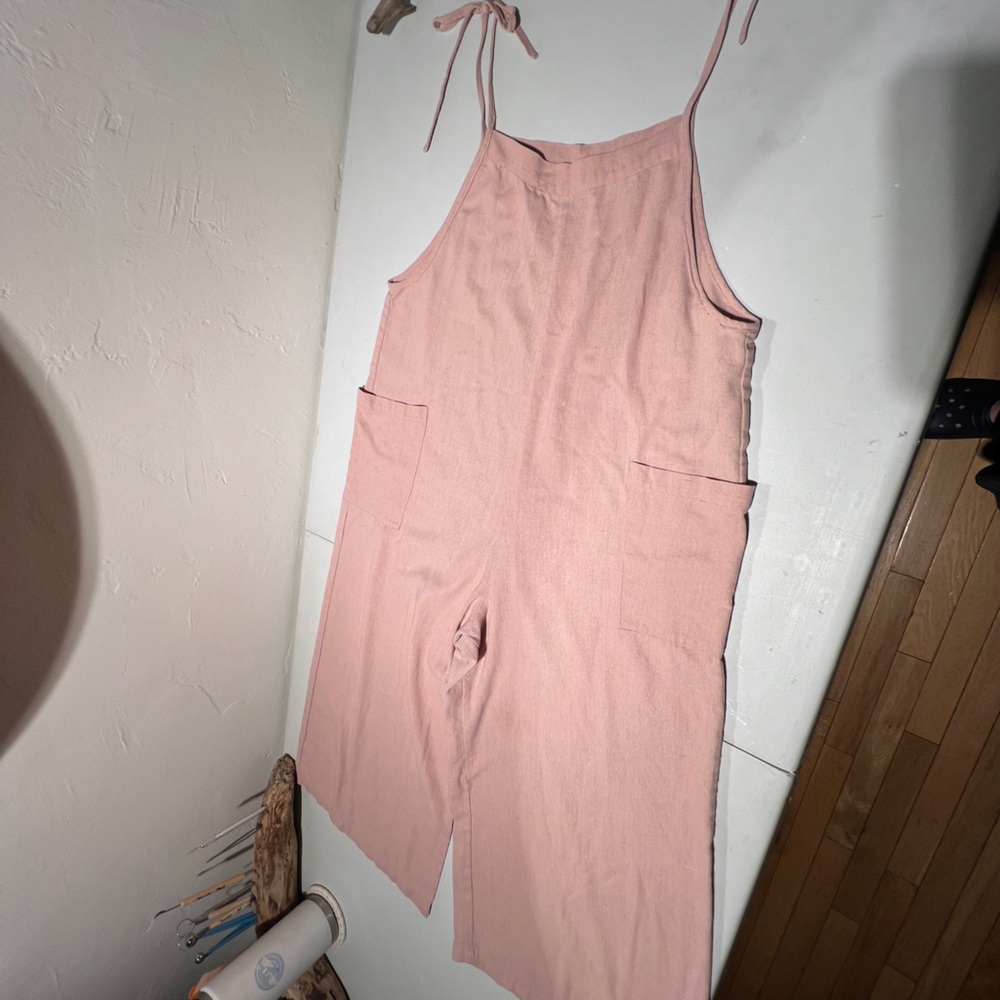 Pink linen romper with tied bows.